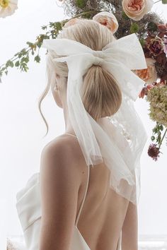 a woman in a white dress with flowers on her head and veil around her neck