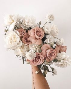 a woman's hand holding a bouquet of white and pink flowers