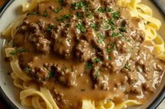 a white plate topped with pasta covered in meat and gravy on top of it