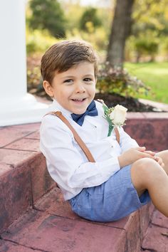 a little boy sitting on the steps with a flower in his lap