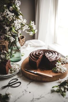 a chocolate cake sitting on top of a wooden cutting board