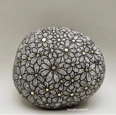 an intricately decorated rock sitting on top of a white surface with gold dots in the middle