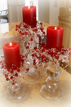 red candles are sitting on top of clear glass vases