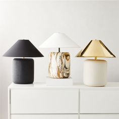 three lamps sitting on top of a white dresser next to each other in different colors