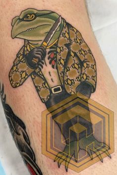 a close up of a person's arm with a tattoo on it and an image of a frog in a suit