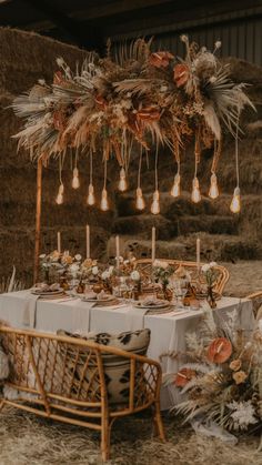 a table set up with candles, flowers and feathers for a wedding or reception in an outdoor setting