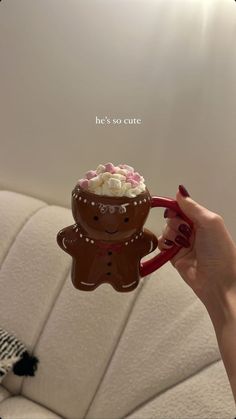 a person holding a cup with some frosting on it and a gingerbread man in the middle