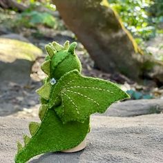 a small green toy sitting on top of a rock