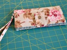 a flowered wallet sitting on top of a cutting board