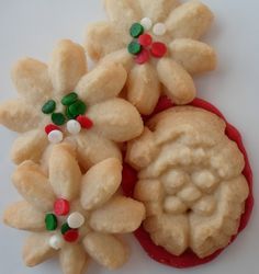 two cookies decorated with candy are sitting on a white surface next to another cookie that is shaped like flowers