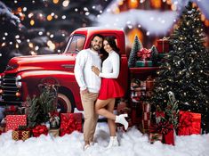 a man and woman standing in front of a red truck surrounded by christmas trees, presents and gifts