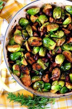 brussel sprouts and mushrooms in a skillet on a yellow checkered tablecloth