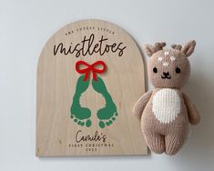 a teddy bear next to a wooden plaque with the name and image of an infant's first christmas