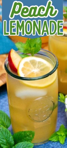 a glass filled with lemonade sitting on top of a blue table next to mint leaves