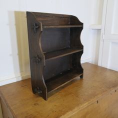 an old wooden bookcase sitting on top of a brown dresser next to a white wall