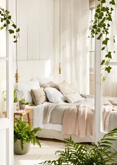 a bedroom with white walls and lots of greenery