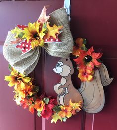 a fall wreath with a squirrel and sunflowers hanging on the front door handle