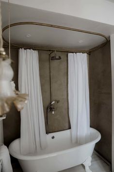 a white bath tub sitting in a bathroom next to a chandelier hanging from the ceiling