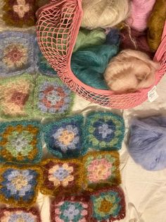 several crocheted grannys are on the table with yarn in baskets and balls of yarn next to them