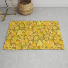 an area rug with yellow and orange flowers on it next to a basket, wicker basket and chair