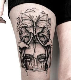 a woman's thigh with a butterfly tattoo on her head and clouds in the background