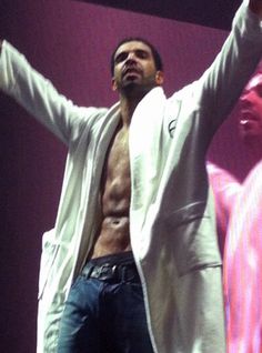 a shirtless man standing on stage with his arms in the air