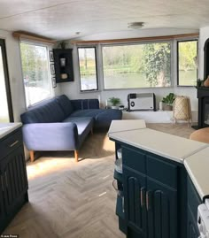 a living room filled with furniture next to a kitchen and dining room table in front of two large windows