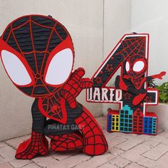 the number four is made out of cardboard and has a spiderman figure next to it