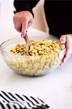 a person scooping food out of a bowl into a glass bowl on top of a table