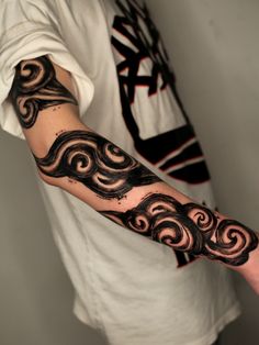 a man's arm with black and white swirls on the arm, in front of a white t - shirt