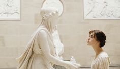 a young man standing next to a statue