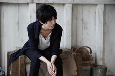 a young man sitting on top of a wooden crate