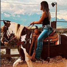 a woman riding on the back of a brown and white horse