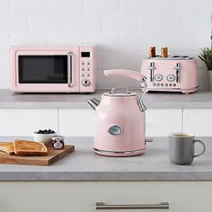 a pink coffee pot sitting on top of a counter next to a toaster oven