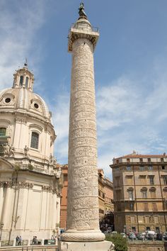 a tall white pillar sitting in the middle of a street next to a large building