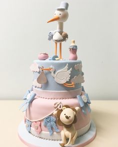 a baby shower cake with a stork, teddy bear and other items on top