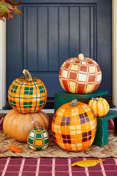 three pumpkins sitting on top of each other in front of a blue door with plaid tablecloth