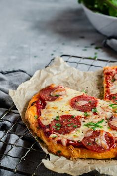 two slices of pepperoni pizza sitting on top of a cooling rack next to a salad