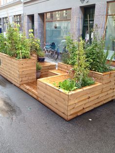 a row of wooden planters sitting on the side of a road next to a building