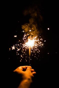 a hand holding a sparkler in the dark