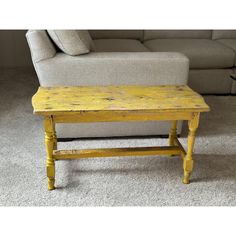 an old yellow table sitting in front of a couch