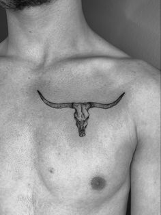 a black and white photo of a man with a bull's head tattoo on his chest