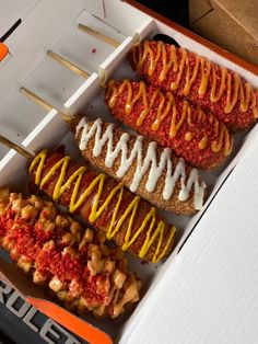 an open box filled with different types of hot dogs and ketchup on skewers