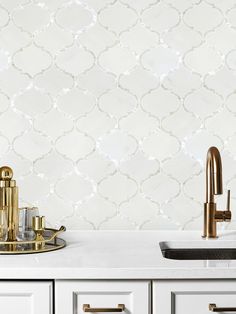 a kitchen with white cabinets and gold faucet in front of the counter top