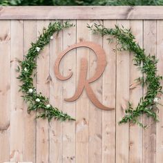 the letter r is made out of wood and surrounded by greenery on a fence