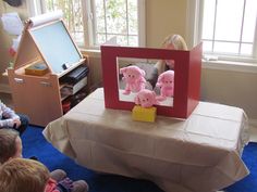 children sitting on the floor in front of a table with stuffed animals and a photo frame