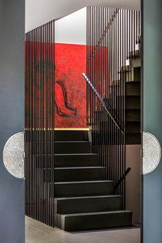 a staircase with black steps leading up to a red painting on the wall behind it