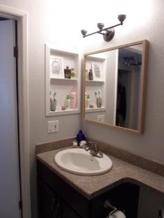 a bathroom sink sitting under a mirror next to a doorway