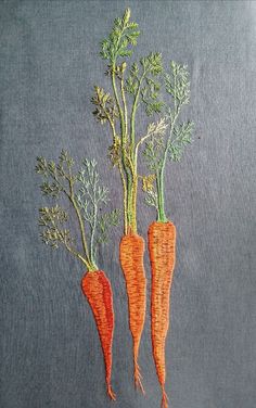 three carrots with green tops on a gray background are embroidered onto the back of a t - shirt