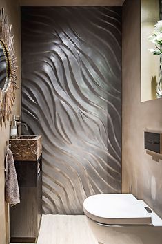 a bathroom with a white toilet sitting next to a wall covered in silver wavy paper